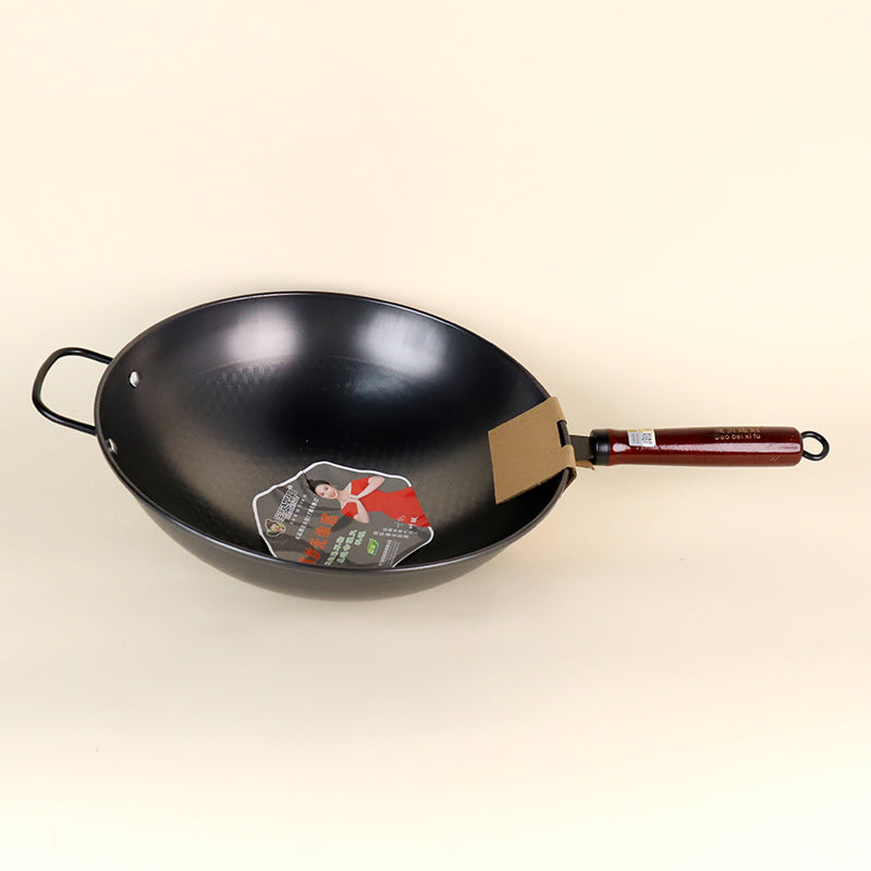 Black wok with a wooden handle on a beige background