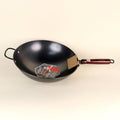 Black wok with a wooden handle on a beige background