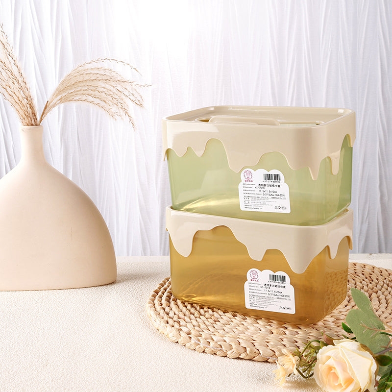 Decorative plant pot with a drip design on a textured surface with a vase and flowers in the background.