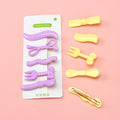 Set of purple and yellow hair clips on a pink background with packaging labeled 'PRINCESS'.