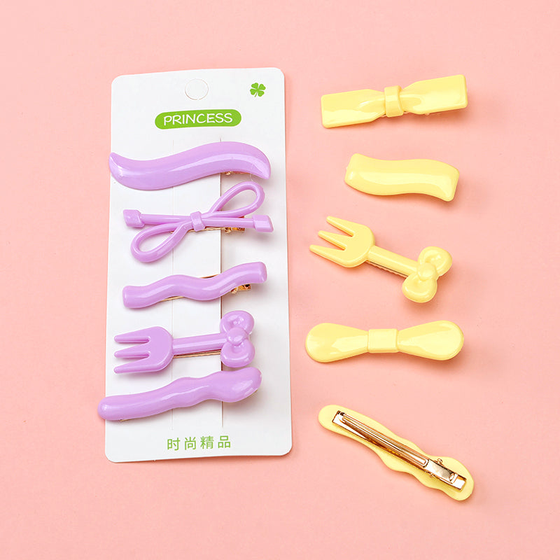 Set of purple and yellow hair clips on a pink background with packaging labeled 'PRINCESS'.