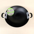 Black wok with a green label on a beige background