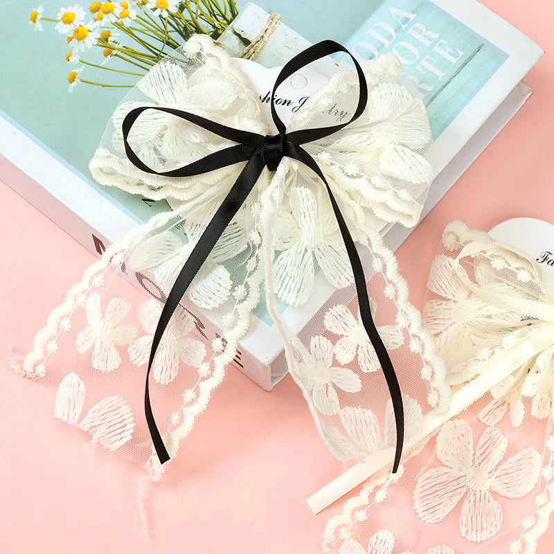 White lace bow with a black ribbon on a pink background