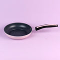 Frying pan with a black speckled interior on a light purple background