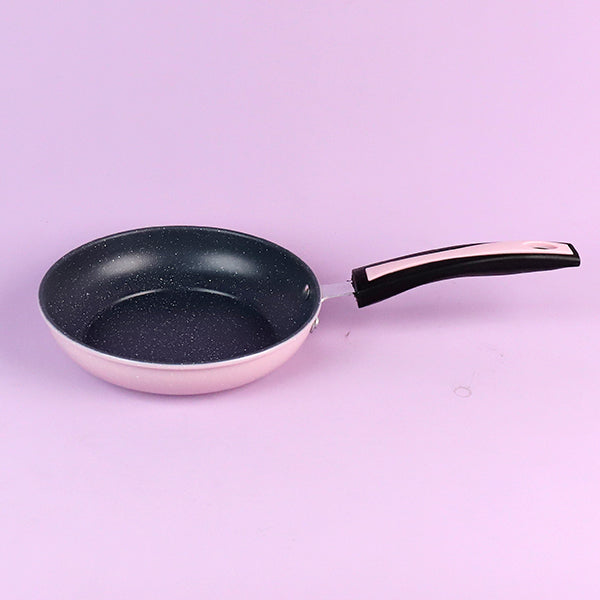 Frying pan with a black speckled interior on a light purple background