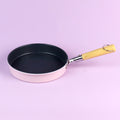 Frying pan with a yellow handle on a light purple background