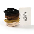 Stack of black, brown, beige, and gold hair ties with a 'Made in China' label on a white background