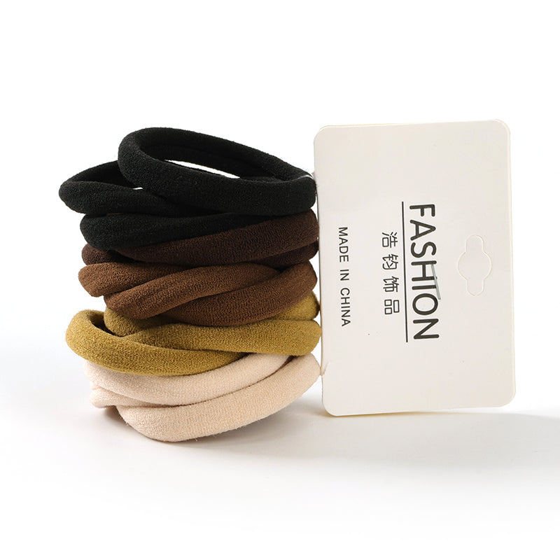 Stack of black, brown, beige, and gold hair ties with a 'Made in China' label on a white background