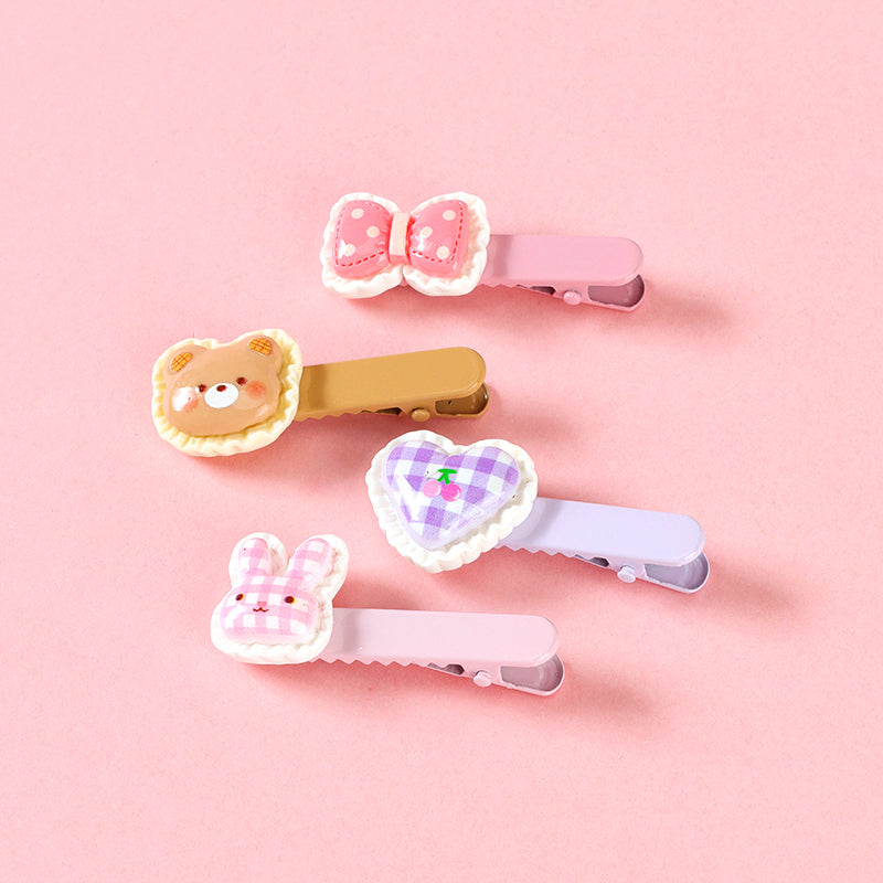 Set of four colorful hair clips on a pink background