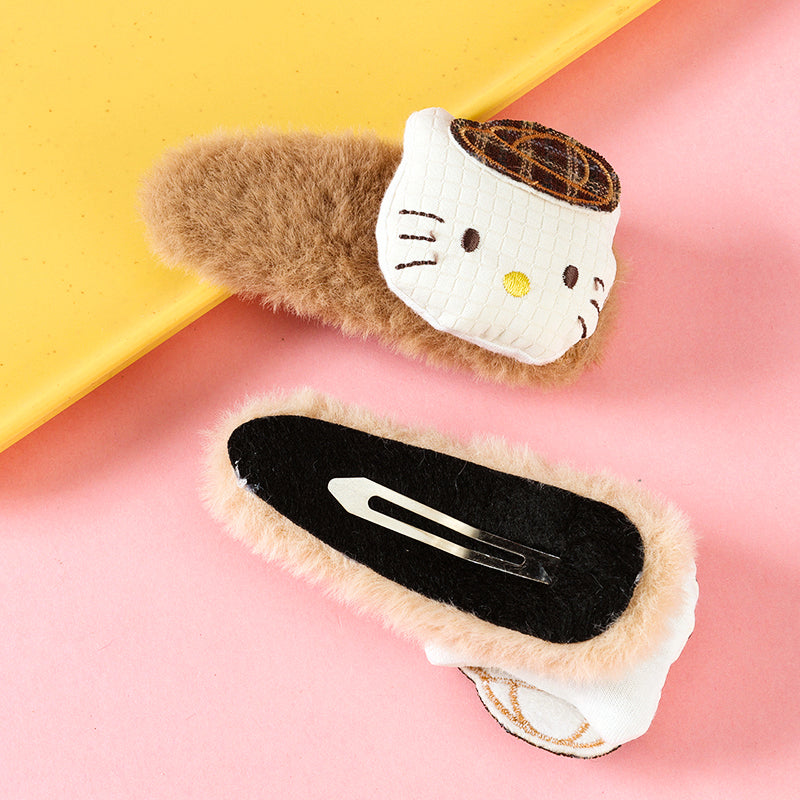 Two cat-shaped hair clips on a pink and yellow background