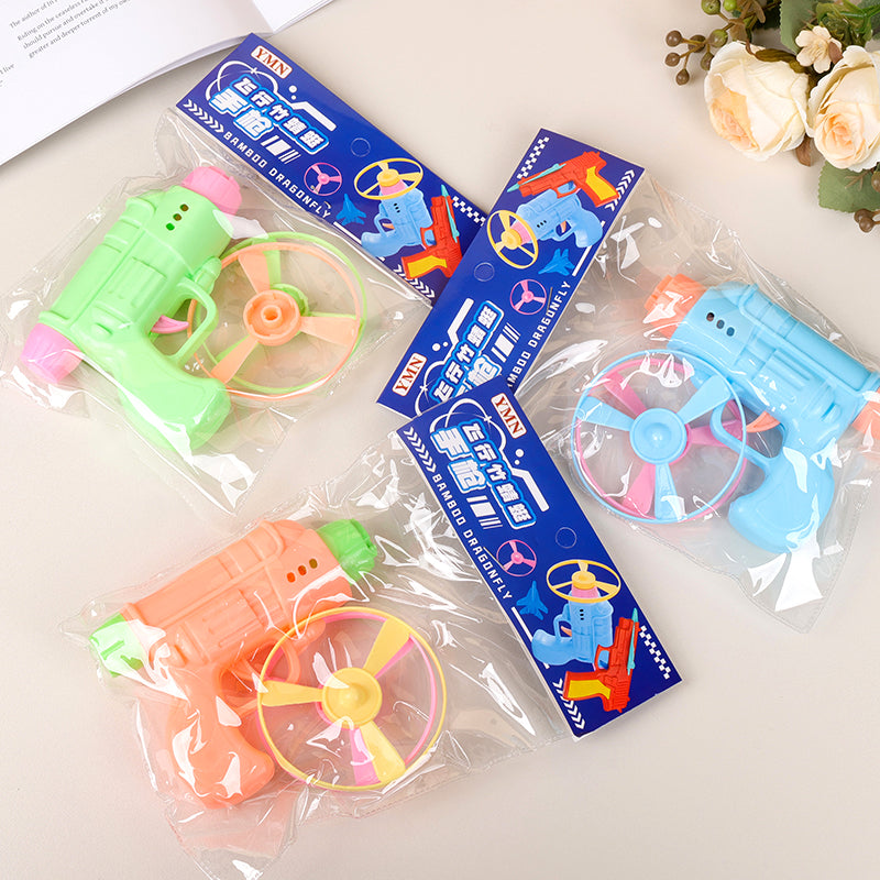 Colorful toy guns with propeller attachments in clear packaging on a light surface.