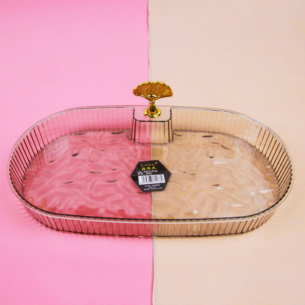 Clear glass tray with gold rim on a pink and beige background