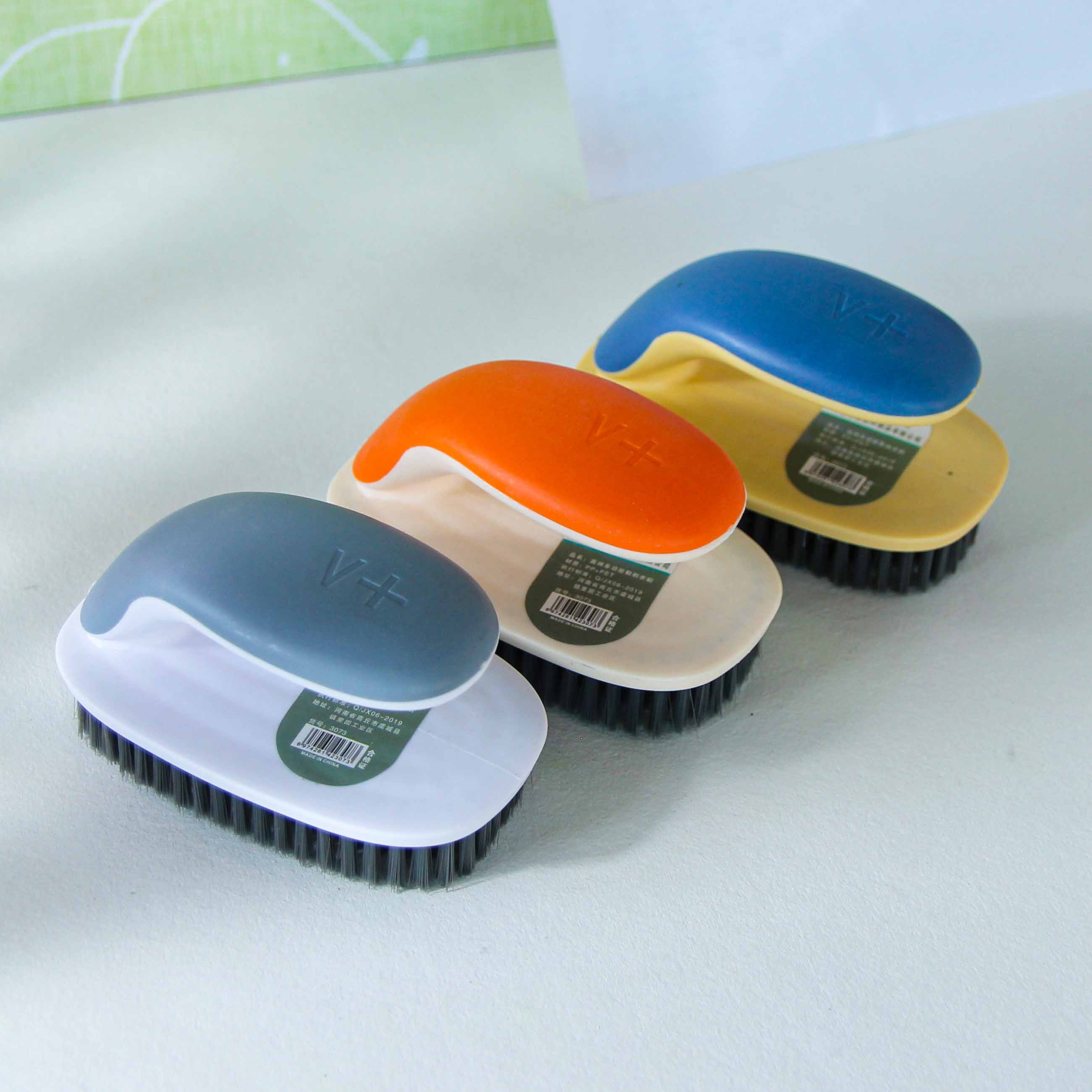 Set of four cleaning brushes with different colored handles on a light surface.
